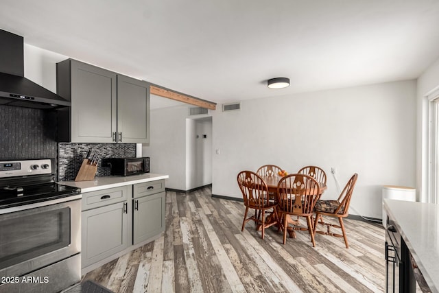 kitchen with wall chimney range hood, backsplash, stainless steel electric stove, and gray cabinets