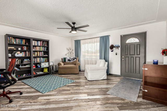 living area with ceiling fan, wood-type flooring, and a textured ceiling