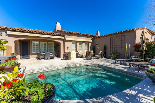 rear view of house featuring a patio, a chimney, an outdoor pool, and stucco siding