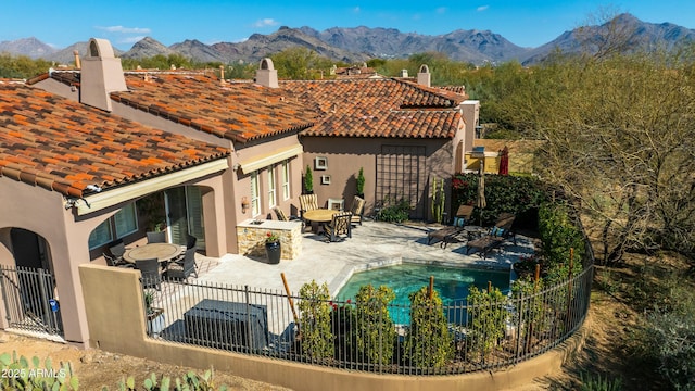 rear view of property featuring stucco siding, a mountain view, a patio, and fence