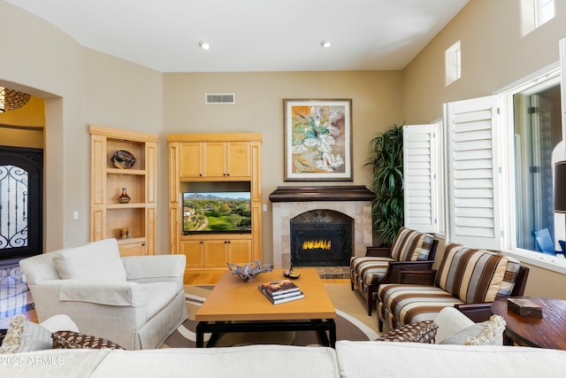 living room featuring recessed lighting, a warm lit fireplace, and visible vents