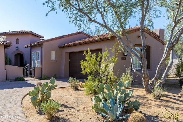 mediterranean / spanish home with driveway, an attached garage, a tile roof, and stucco siding