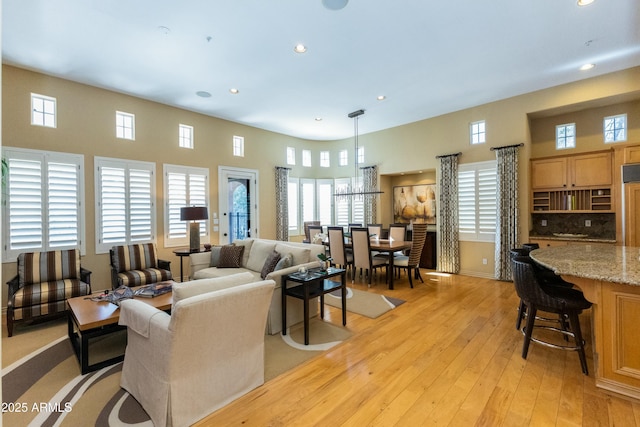 living room featuring light wood finished floors, a high ceiling, and recessed lighting