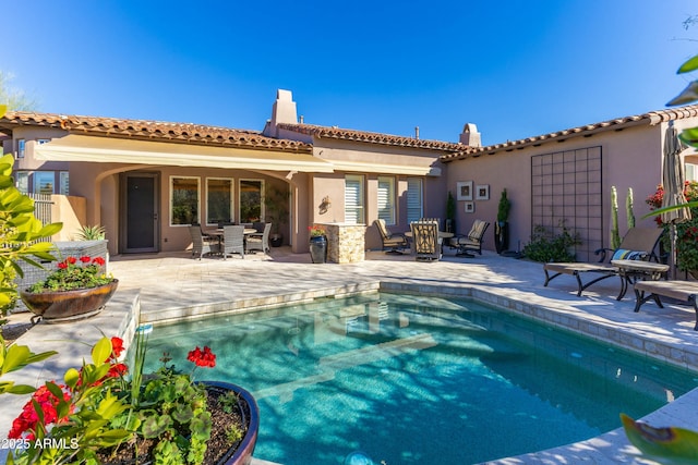 back of property featuring a patio area, an outdoor pool, and stucco siding