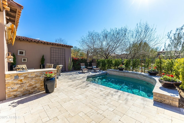 view of pool featuring a pool, a patio, a bar, and fence