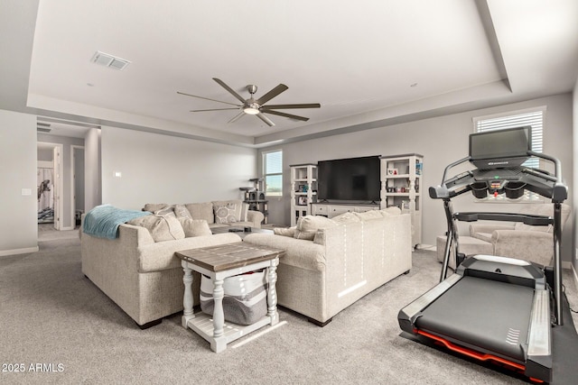 living room with carpet floors, ceiling fan, and a tray ceiling