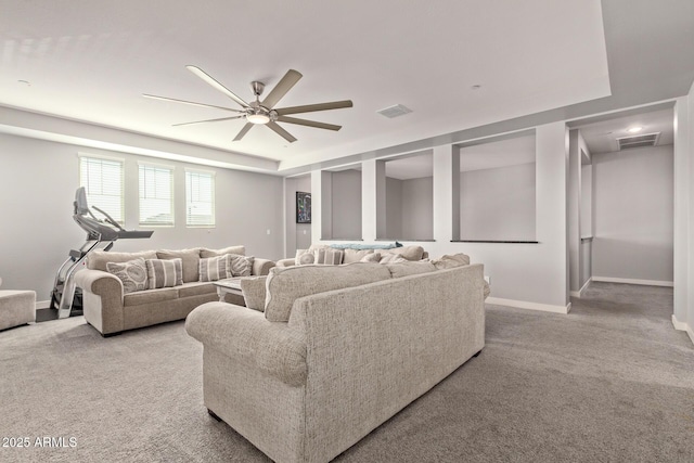 living room featuring light carpet, ceiling fan, and a tray ceiling