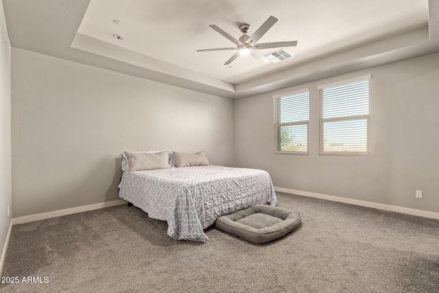 bedroom with carpet flooring, ceiling fan, and a tray ceiling