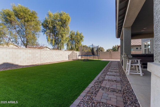 view of yard featuring a hot tub, a trampoline, and a patio