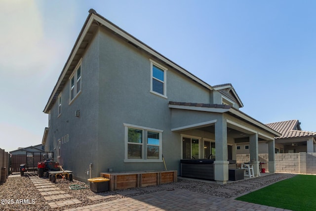 back of house with a patio area and a hot tub