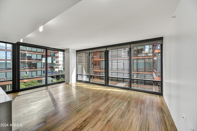 unfurnished room with hardwood / wood-style floors and expansive windows