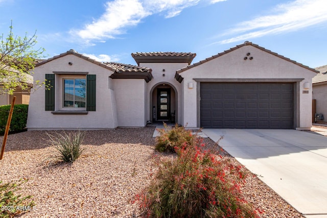 mediterranean / spanish house featuring driveway, an attached garage, a tiled roof, and stucco siding