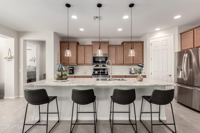 kitchen with light tile patterned floors, visible vents, brown cabinets, stainless steel appliances, and a sink