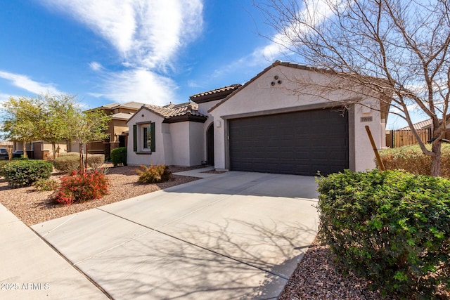 mediterranean / spanish-style house featuring a garage, fence, a tiled roof, driveway, and stucco siding