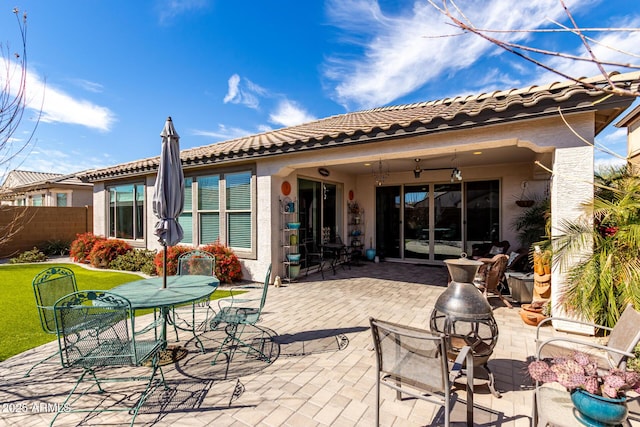 back of house with outdoor dining space, a patio area, fence, and stucco siding