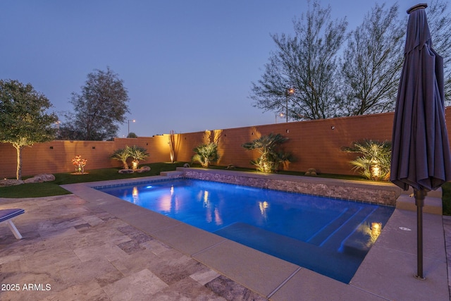 pool at dusk with a patio area