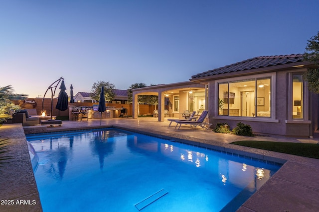 pool at dusk featuring an outdoor fire pit and a patio area