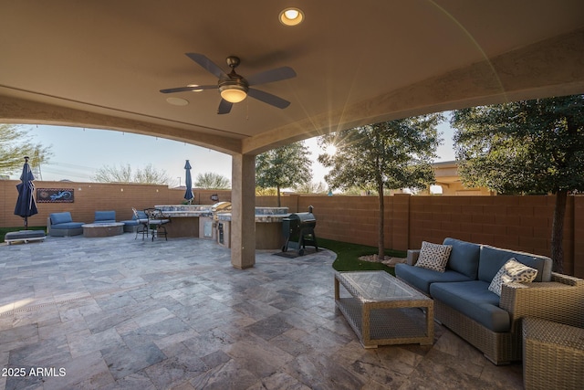 view of patio featuring area for grilling, an outdoor living space with a fire pit, ceiling fan, and an outdoor kitchen