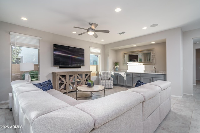 living room with ceiling fan, wet bar, and a wealth of natural light