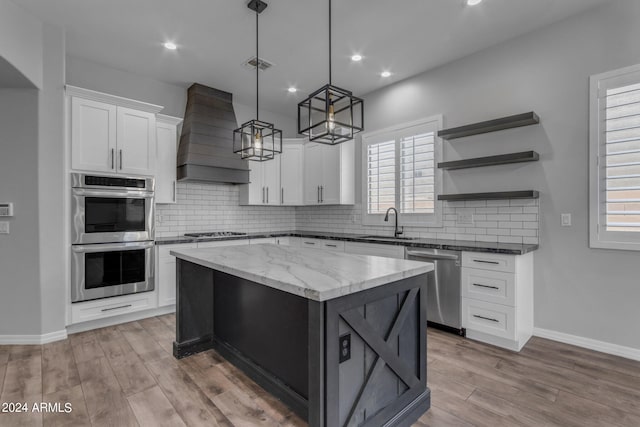 kitchen featuring a kitchen island, a wealth of natural light, stainless steel appliances, white cabinets, and pendant lighting