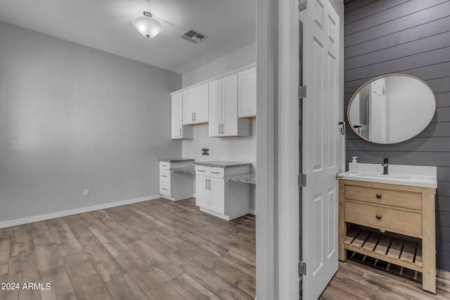 kitchen with light stone countertops, light hardwood / wood-style floors, sink, and white cabinetry