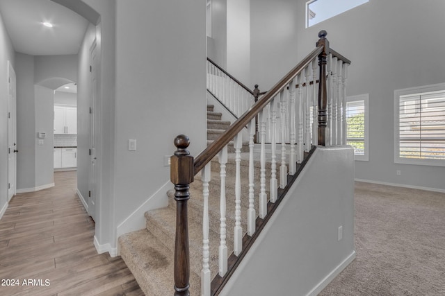 staircase with hardwood / wood-style flooring and a towering ceiling