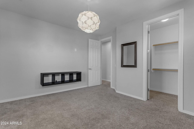 unfurnished bedroom with a walk in closet, a closet, and light colored carpet