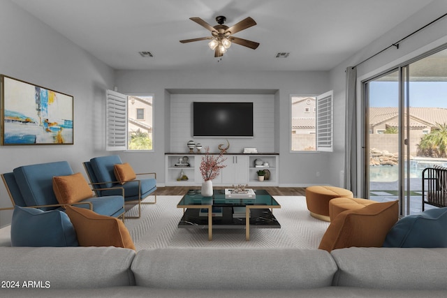 living room with plenty of natural light, wood-type flooring, and ceiling fan