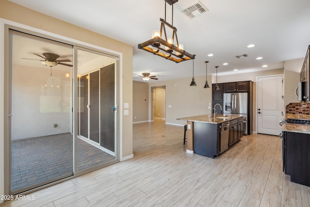 9921 E Acceleration Dr, Mesa, AZ 85212 - kitchen featuring a ceiling fan, recessed lighting, a breakfast bar area, light stone countertops, and dark brown cabinets