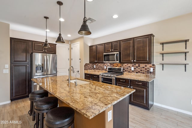 9921 E Acceleration Dr, Mesa, AZ 85212 - kitchen with appliances with stainless steel finishes, a sink, a kitchen breakfast bar, dark brown cabinetry, and baseboards