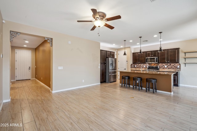 9921 E Acceleration Dr, Mesa, AZ 85212 - kitchen with stainless steel appliances, a ceiling fan, dark brown cabinets, a kitchen bar, and backsplash
