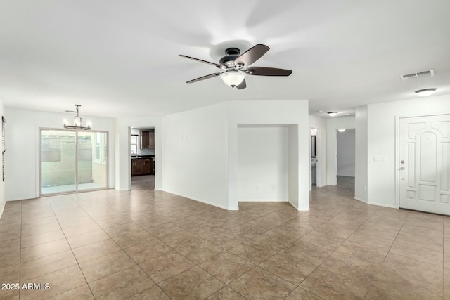 tiled empty room with visible vents, ceiling fan with notable chandelier, and baseboards