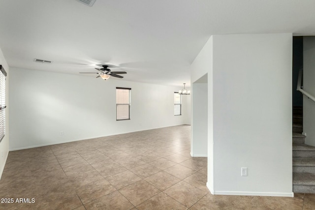 empty room with visible vents, ceiling fan with notable chandelier, light tile patterned floors, baseboards, and stairs