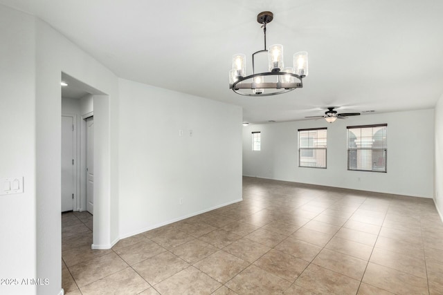 unfurnished room with light tile patterned floors, ceiling fan with notable chandelier, and baseboards