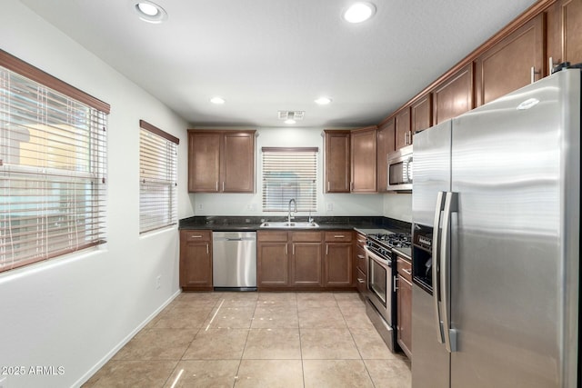 kitchen featuring dark countertops, light tile patterned floors, recessed lighting, appliances with stainless steel finishes, and a sink