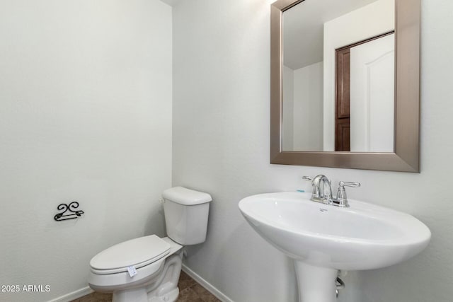 bathroom with a sink, baseboards, and toilet