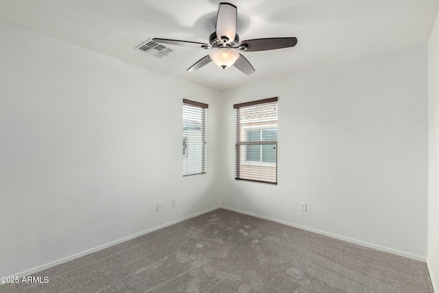 carpeted spare room with visible vents, a ceiling fan, and baseboards