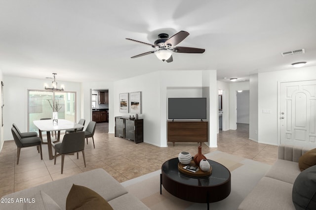 living area featuring light tile patterned floors, visible vents, baseboards, and ceiling fan with notable chandelier