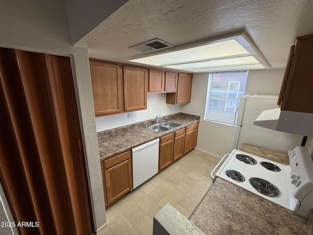 16602 N 25th St Unit 217, Phoenix, AZ 85032 - kitchen with white appliances, a sink, a textured ceiling, brown cabinetry, and baseboards