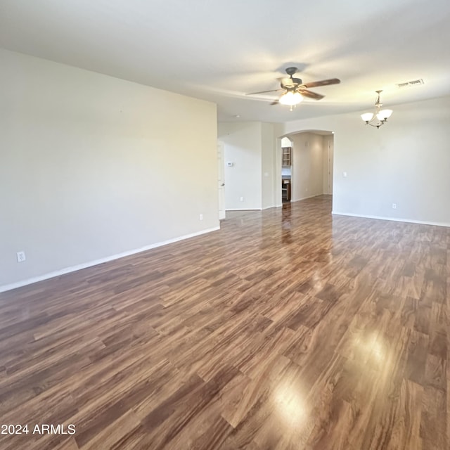 empty room featuring ceiling fan with notable chandelier and dark hardwood / wood-style floors