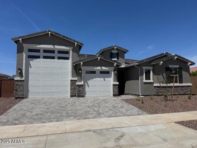view of front of home with a garage, stucco siding, decorative driveway, and stone siding
