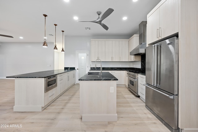 kitchen featuring wall chimney exhaust hood, sink, ceiling fan, and high quality appliances