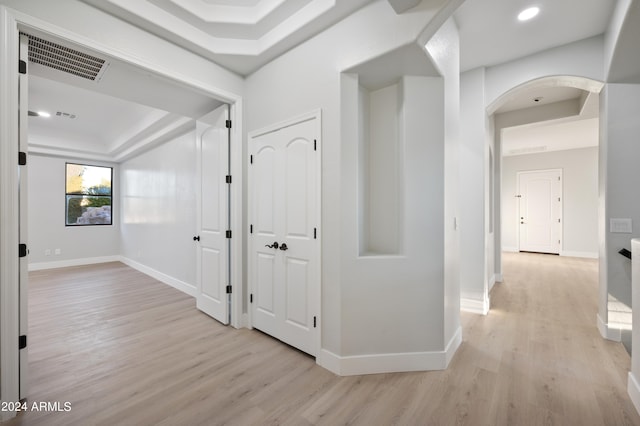 corridor with light hardwood / wood-style flooring and a raised ceiling