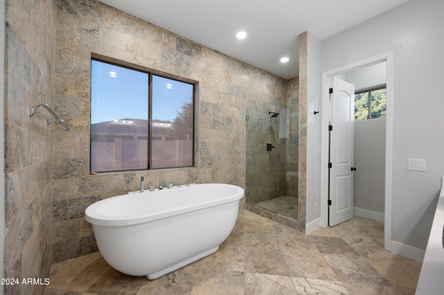 bathroom featuring plus walk in shower and tile walls