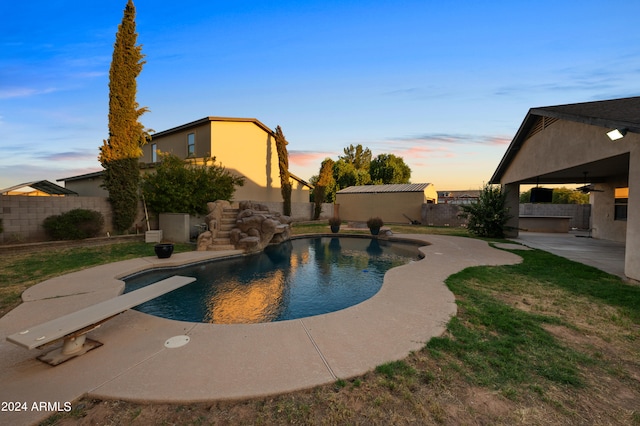 pool at dusk with a diving board and a patio area