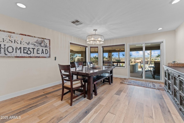 dining area featuring visible vents, baseboards, light wood-type flooring, and an inviting chandelier