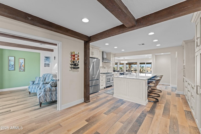 kitchen with visible vents, backsplash, wall chimney range hood, beamed ceiling, and high quality appliances