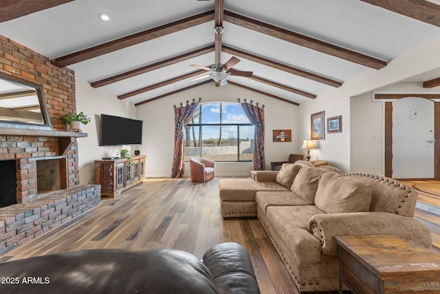 living area featuring a fireplace, lofted ceiling with beams, a ceiling fan, and hardwood / wood-style flooring