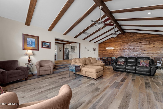 living room featuring wood walls, beam ceiling, wood finished floors, high vaulted ceiling, and a ceiling fan