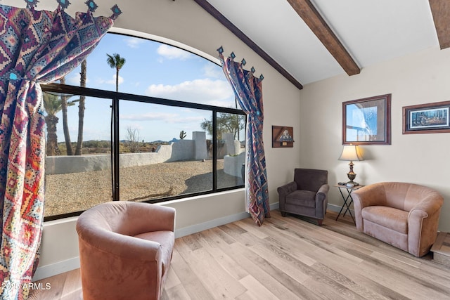 sitting room featuring lofted ceiling with beams, baseboards, and wood finished floors